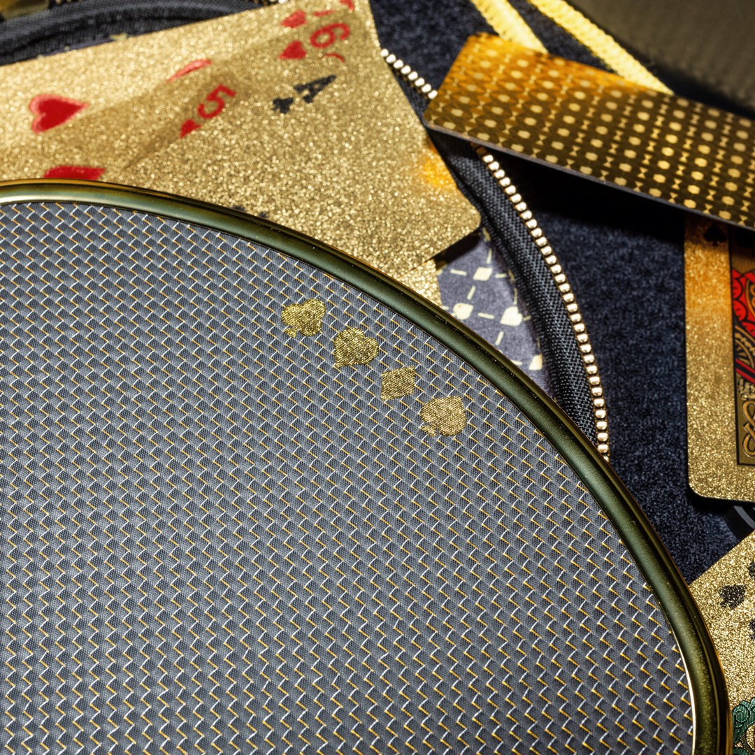 Close-up of the High Roller pickleball paddle beside gold playing cards