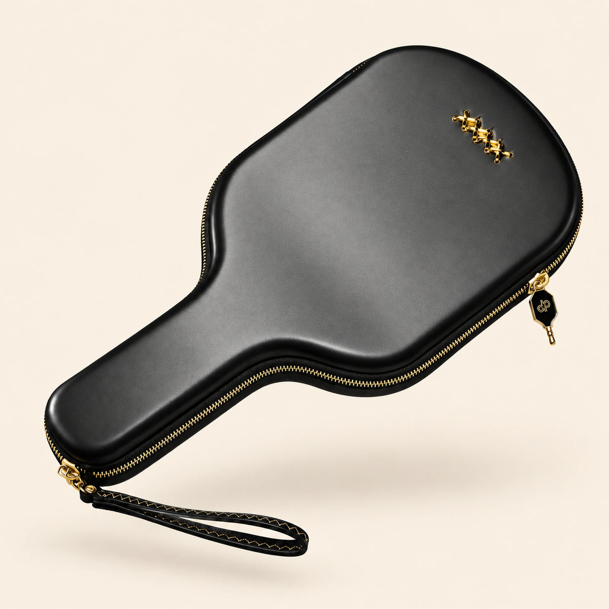 Full back view of the black High Roller paddle case with gold crossed stitches, gold zipper and wrist loop, floating on cream.