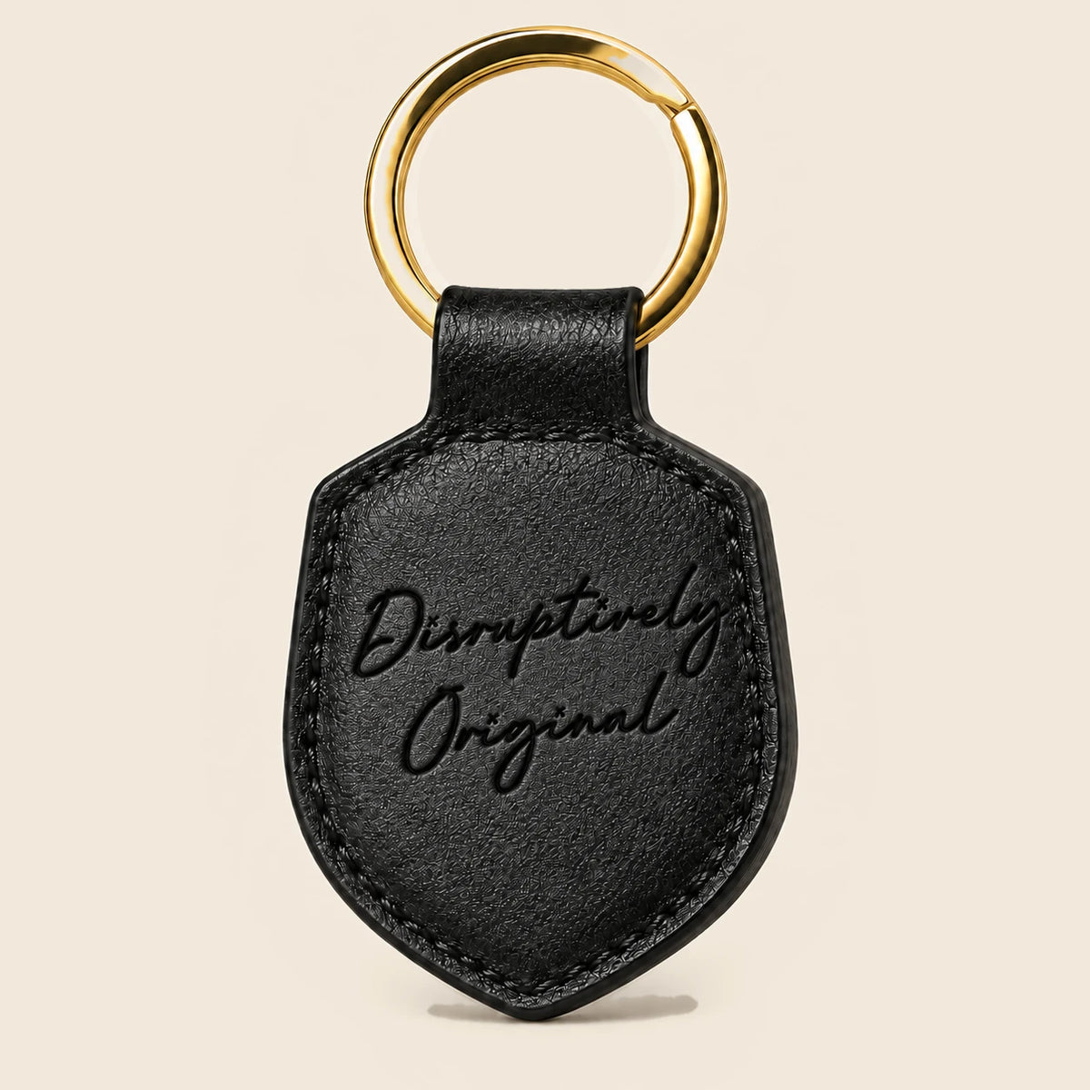 Reverse of the black leather keychain with Disruptively Original script debossed into leather, finished edges and gold split ring.