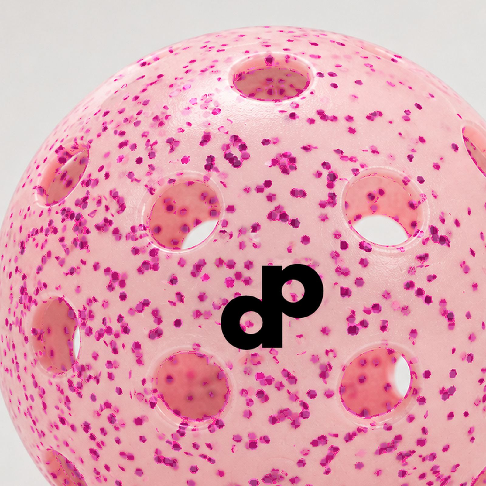 Macro close-up of pink glitter inside a translucent outdoor pickleball