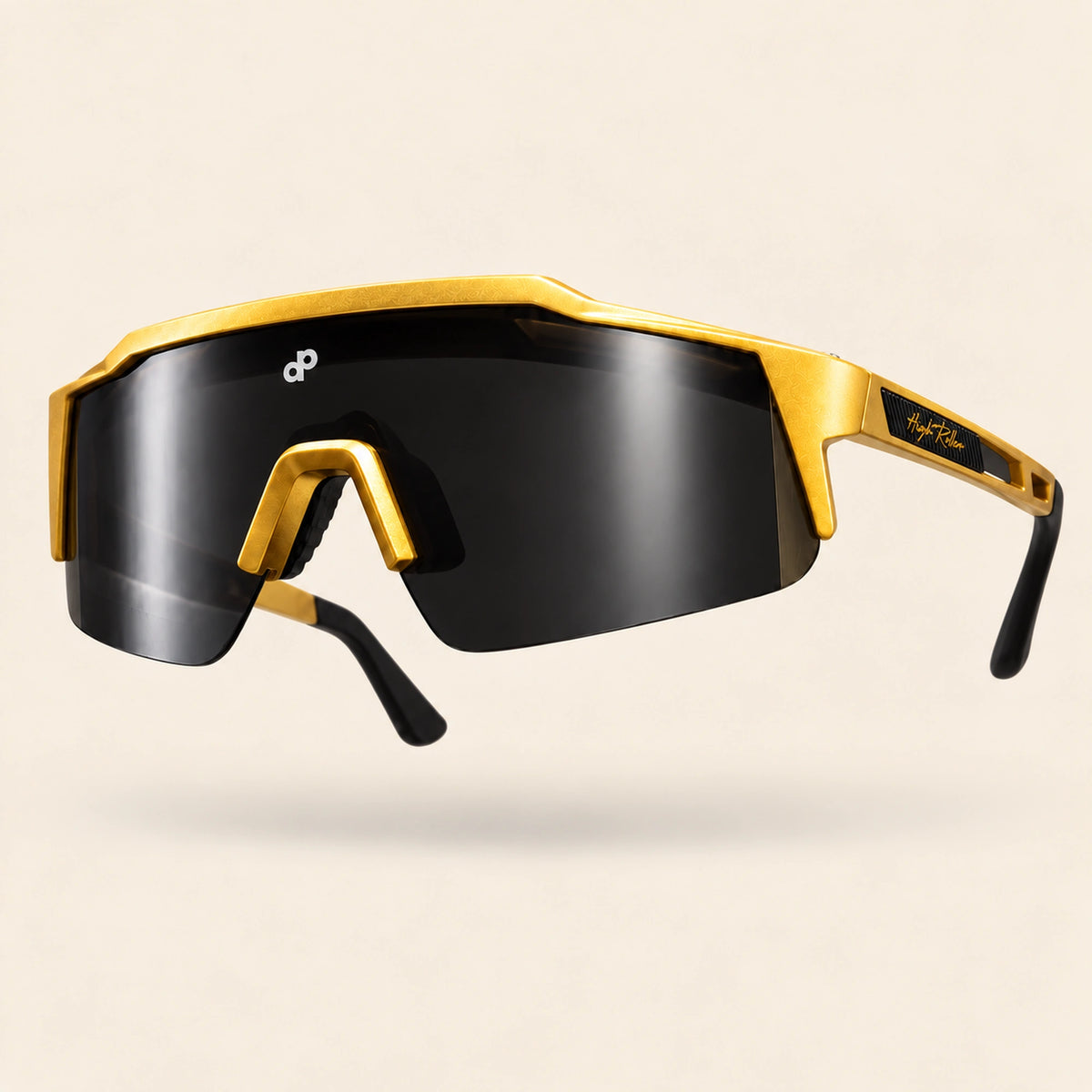 Full low-front view of the gold High Roller sunglasses showing the shield contour and nose arch on cream.
