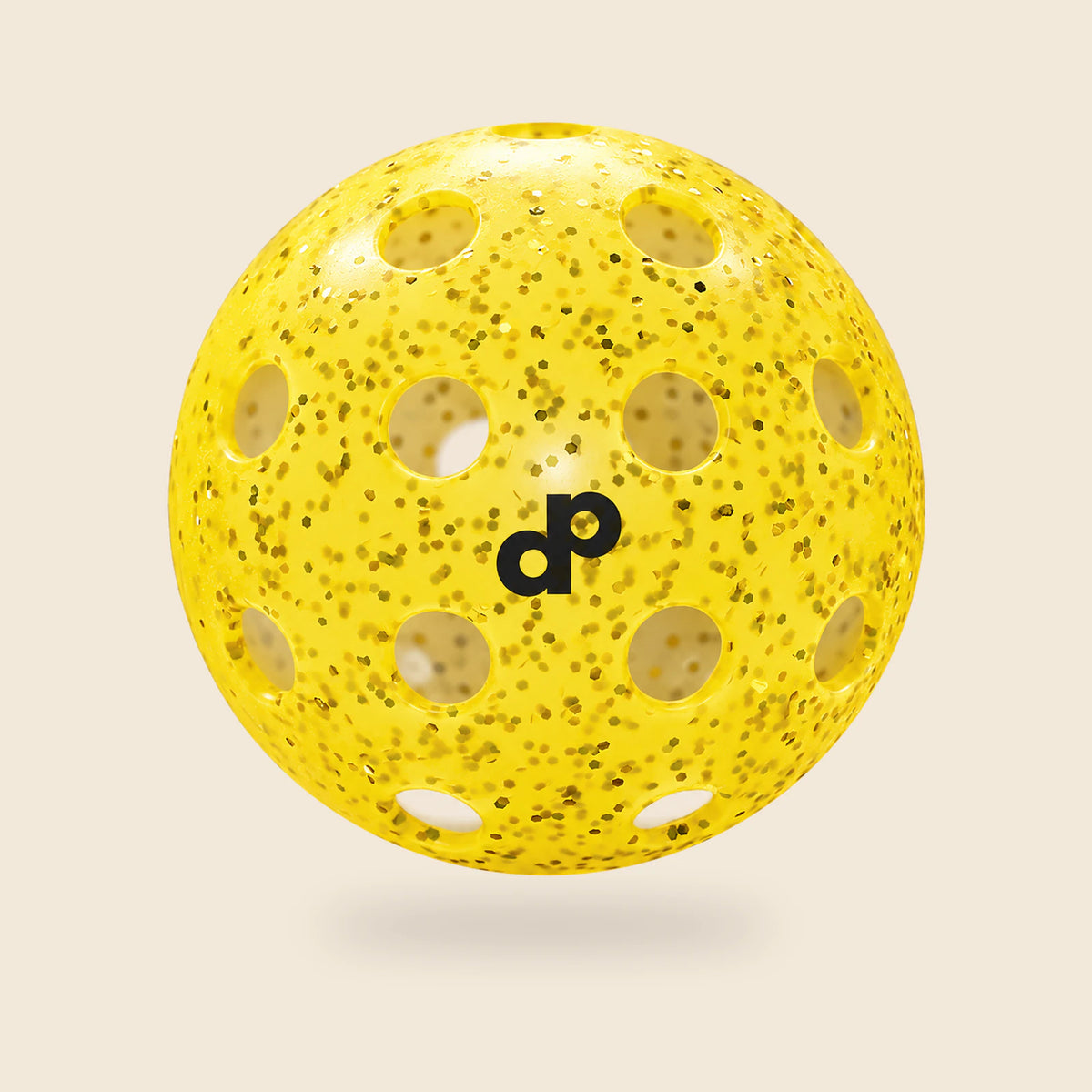 Single yellow DOPE glitter pickleball with black DP logo and circular holes, floating on cream.