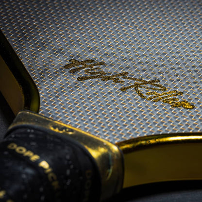 Extreme closeup showing the "High Roller" logo and the texture of the 3K Gold Weave Carbon Fiber surface.