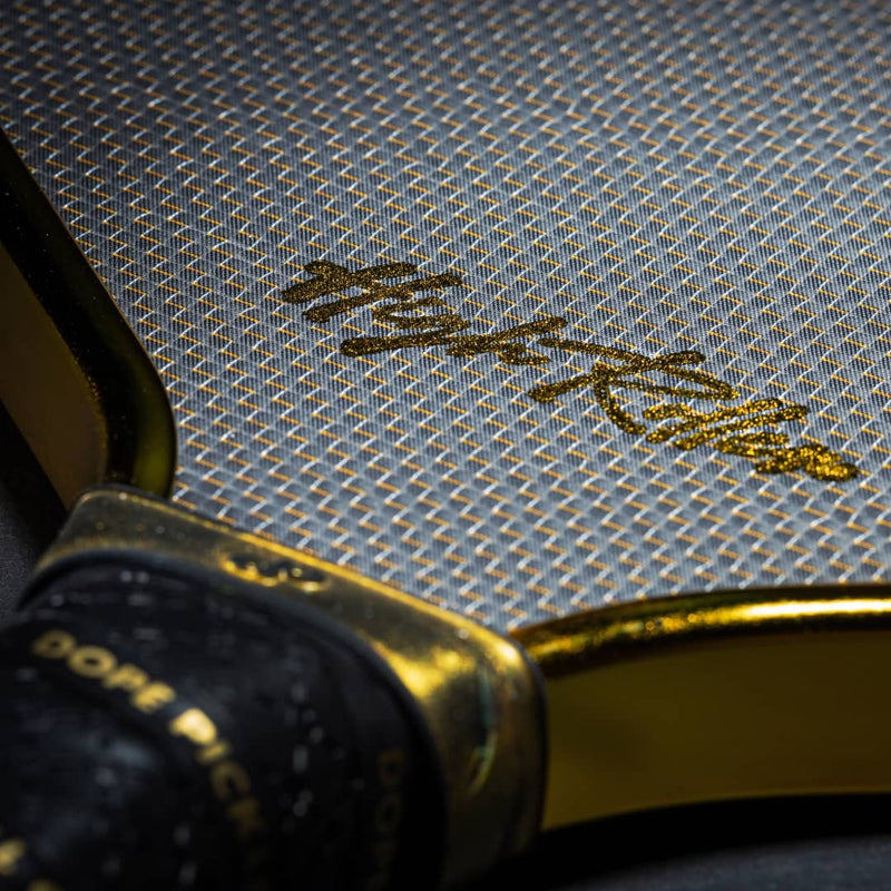 Close-up of High Roller lettering on a black paddle face with a gold mesh pattern