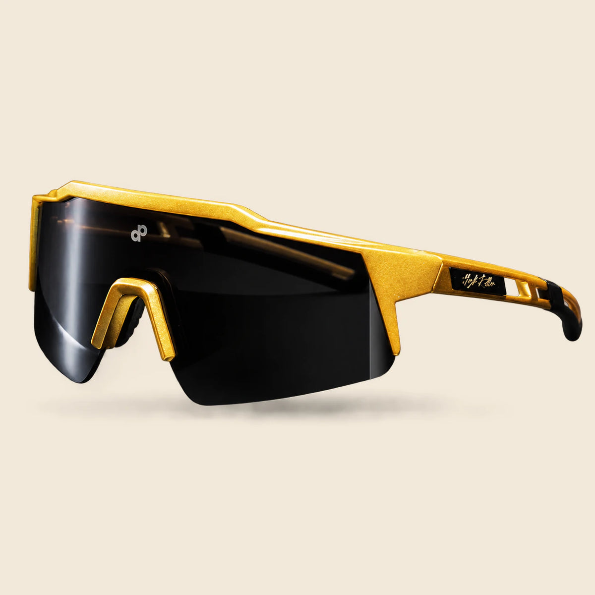 High Roller black shield sunglasses with the angular gold brow, small white DP lens mark, complete gold temple and black tip, presented from the original wide photograph on warm cream.