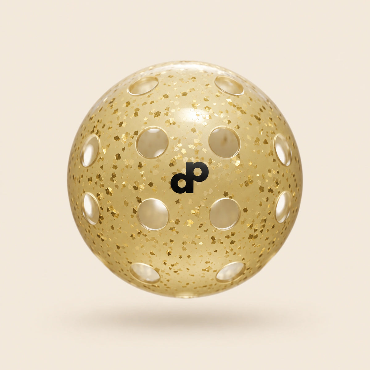Single DOPE High Roller gold glitter pickleball with black DP logo, circular holes and gold foil flakes, floating on cream.