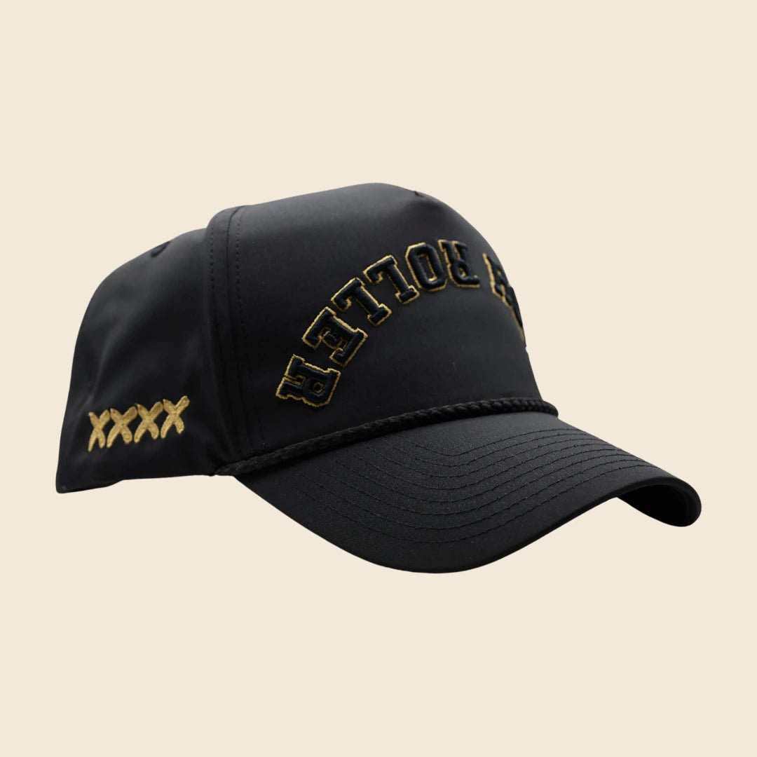 Three-quarter view of a black High Roller hat with gold lettering and gold side stitches