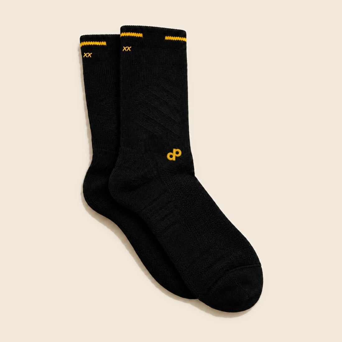 High Roller sock pair folded through the center back on theme cream, with two small gold Permanent Marker Xs visible at each left rear fold, the remaining back stitches hidden around the fold, gold DP at the forward outside ankle and cuff-line side gaps.