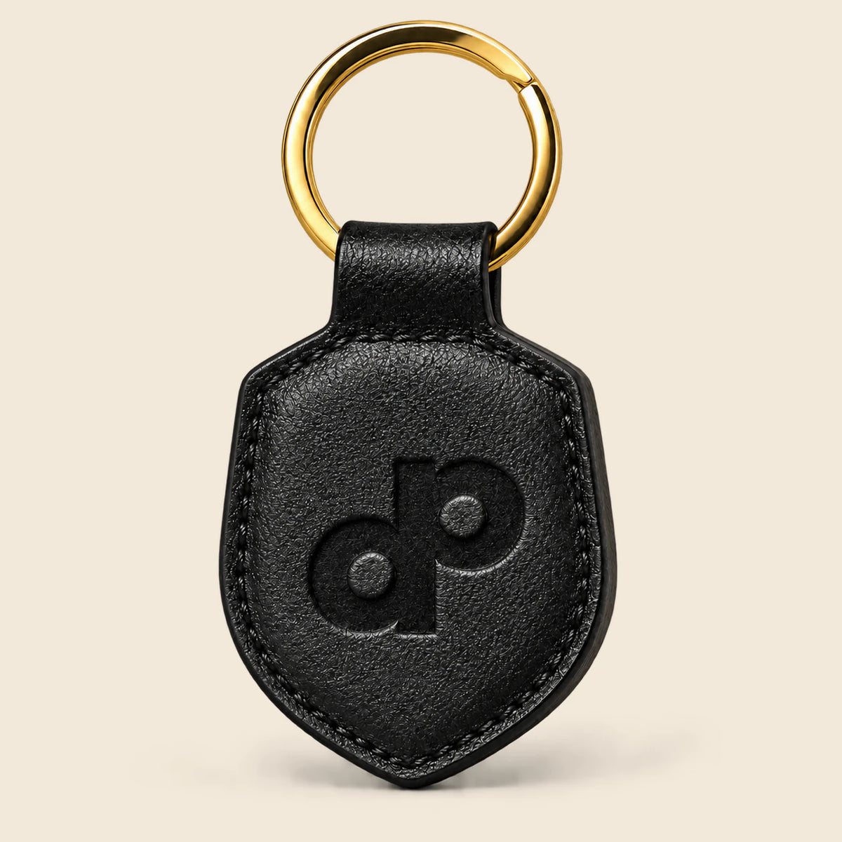 Black leather paddle-shaped keychain with debossed DP monogram, finished edges and a gold-tone split ring.