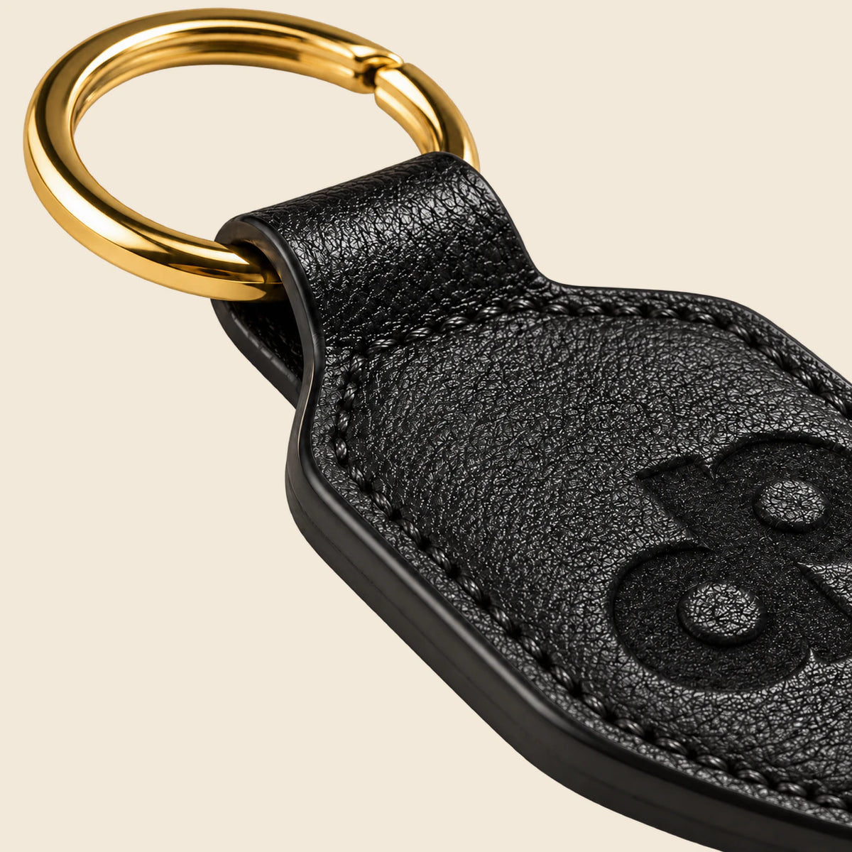 Close-up of the finished black leather edges, perimeter stitching and gold-tone ring.
