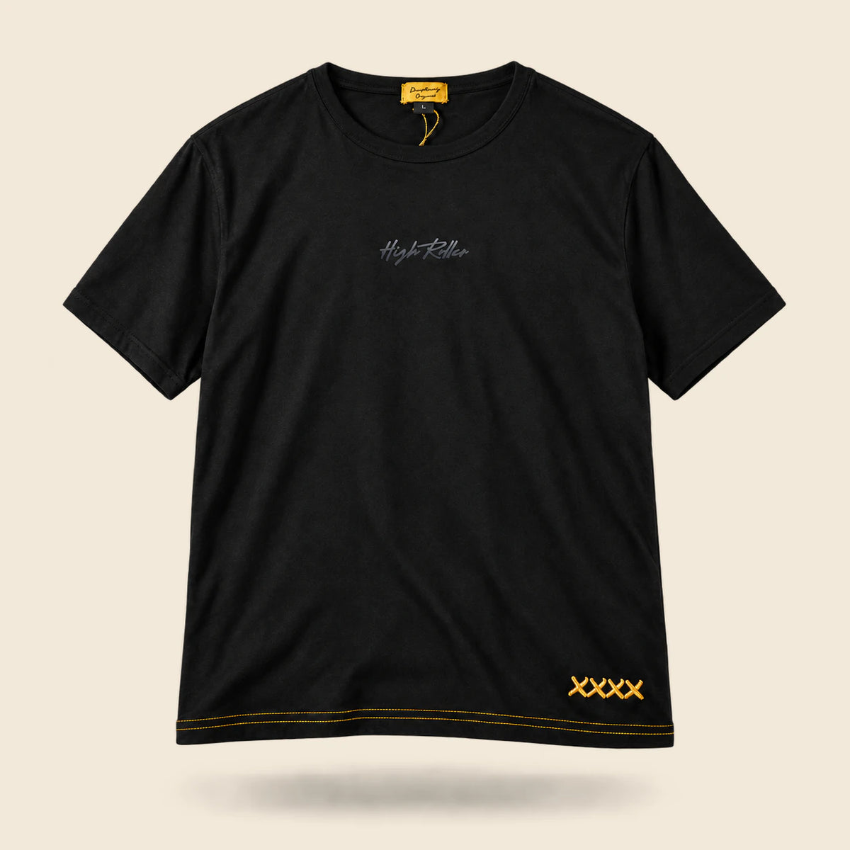 Full front of the black High Roller lounge T-shirt with tonal script, gold collar label, gold hem stitching and four linked gold X stitches, shown with natural drape on warm cream.