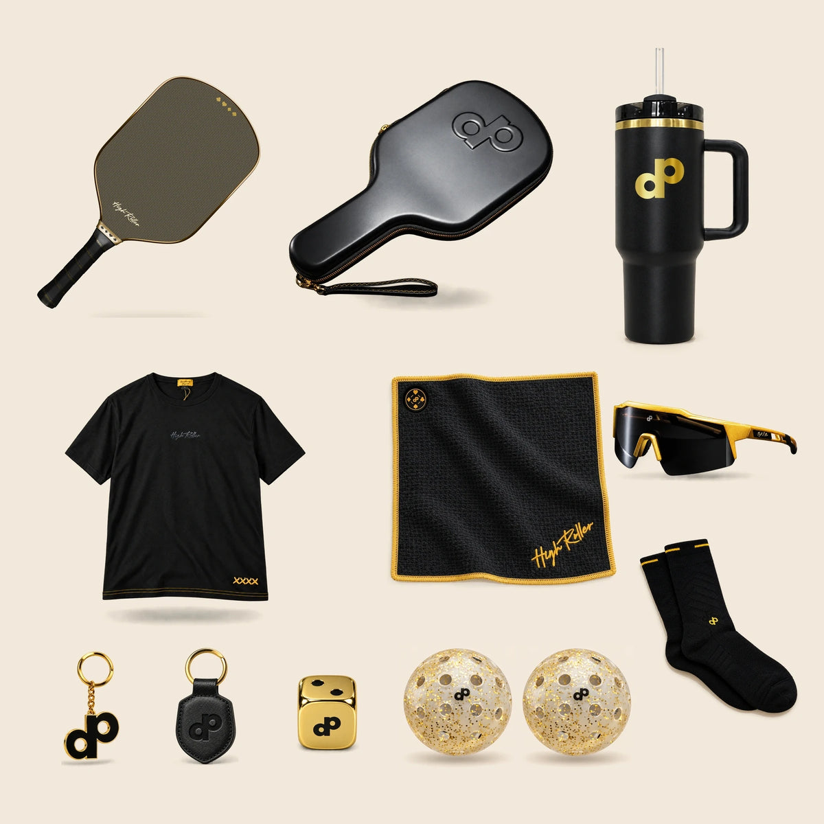 High Roller bundle on cream: one paddle, travel case, T-shirt, sunglasses, tumbler, magnetic towel, gold keychain, leather keychain, pair of socks, one gold die and two gold-glitter pickleballs.