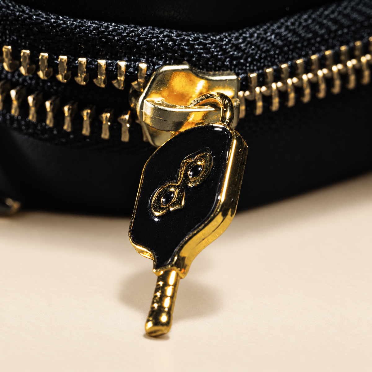 Close view of the gold paddle-shaped zipper pull and DP mark on the High Roller case.