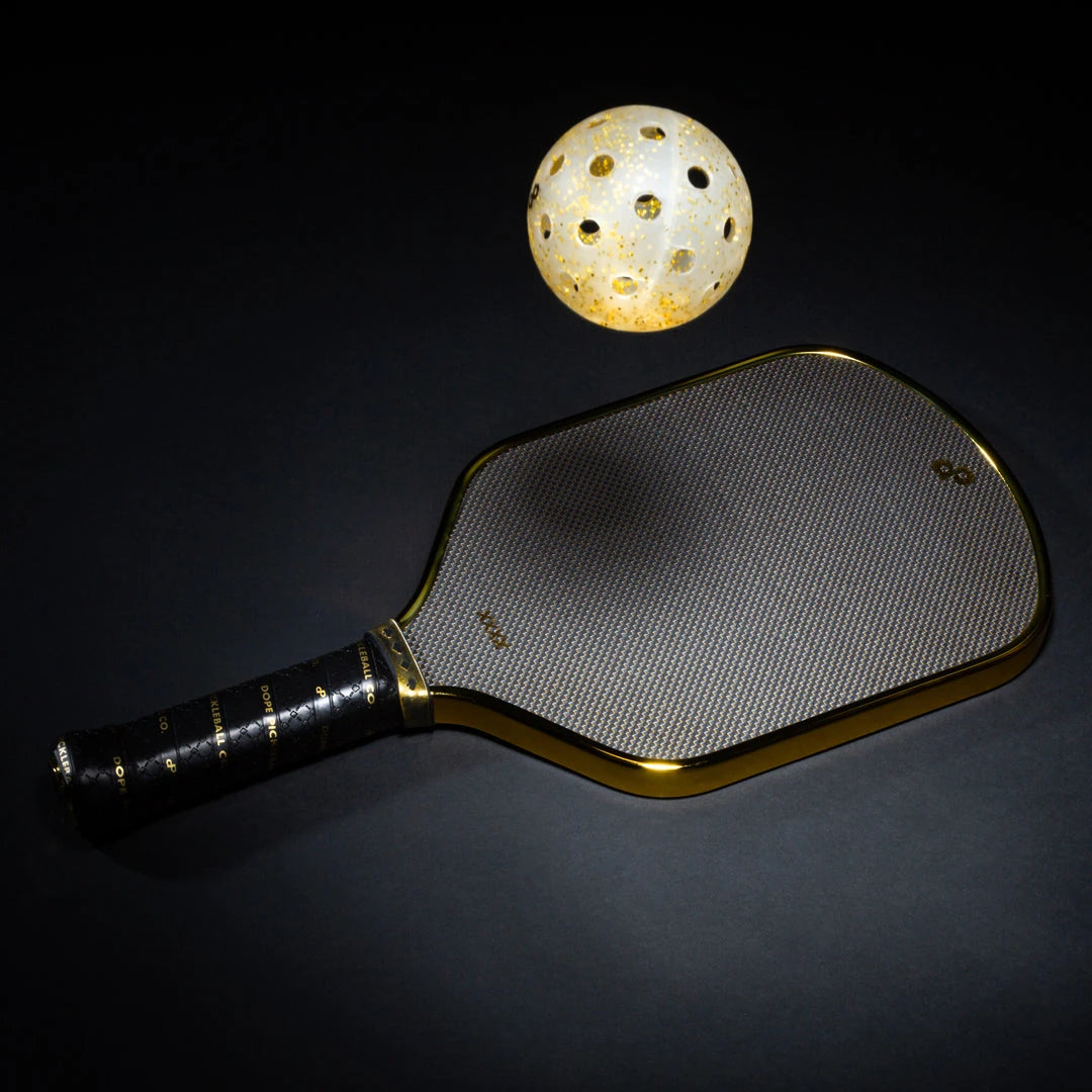Original low-angle photograph of the High Roller metallic chrome-gold paddle with a gold-glitter pickleball. Ball sold separately.