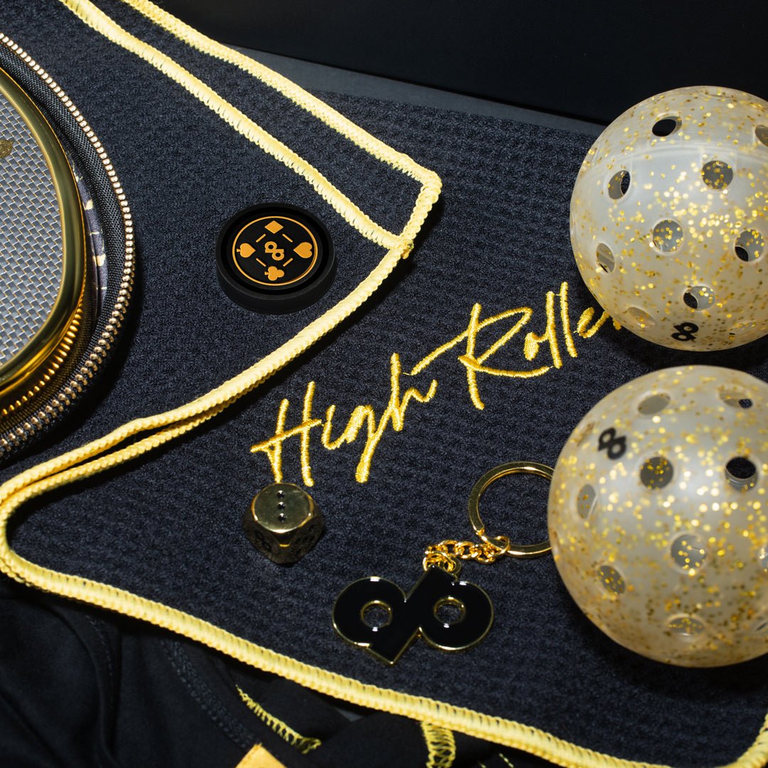 Original photograph of the High Roller towel showing its sewn magnet, gold edge stitching and embroidered script with other collection accessories.