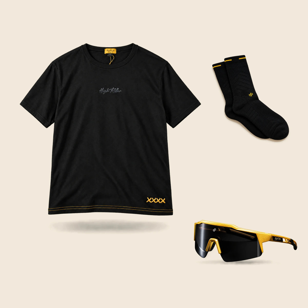 High Roller Lounge T-shirt, one pair of black and gold performance socks, and black and gold sunglasses arranged on cream.