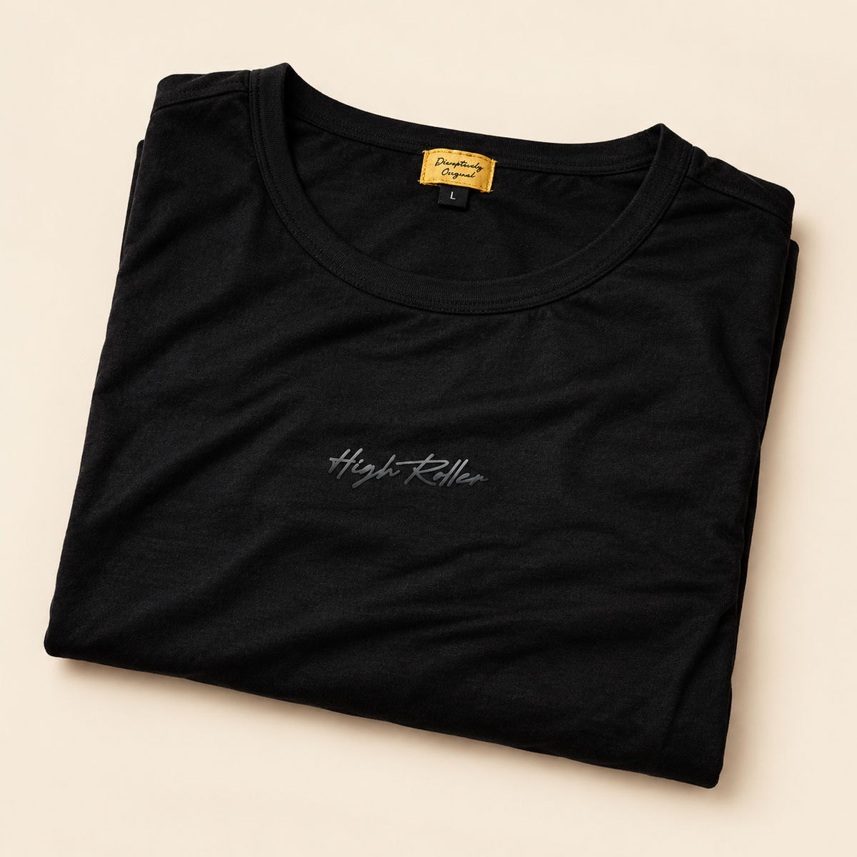Neatly folded black High Roller shirt with the bottom hem tucked underneath, subtle chest script, sewn gold collar label and no loose tag cord.