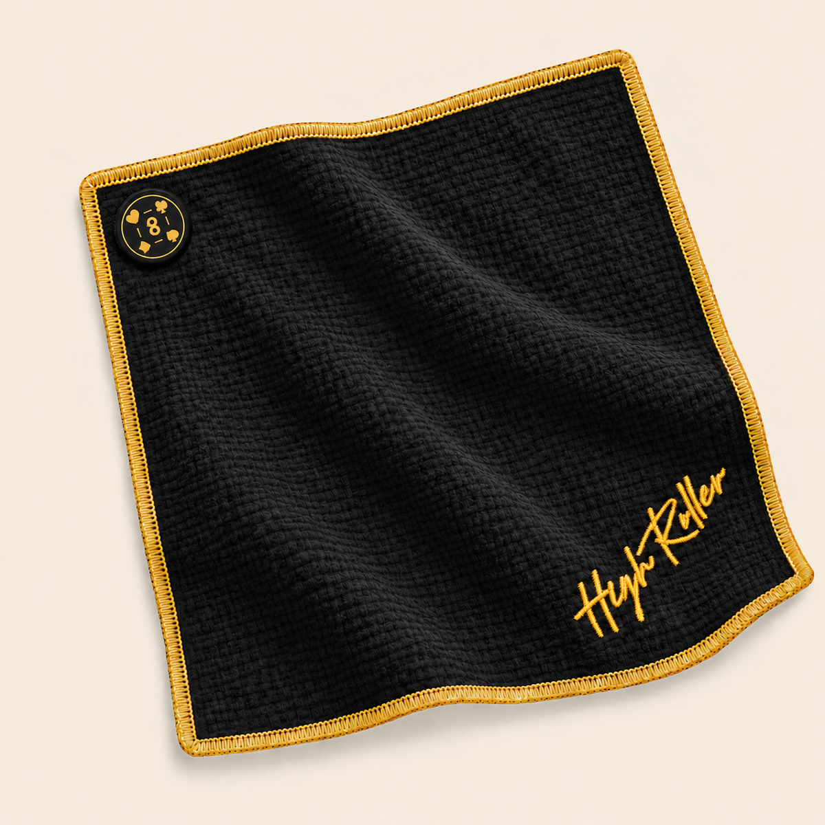 Full High Roller towel laid flat on cream, with soft black waffle fabric, gold embroidered script, gold stitching and the sewn magnet aligned with the towel edges.