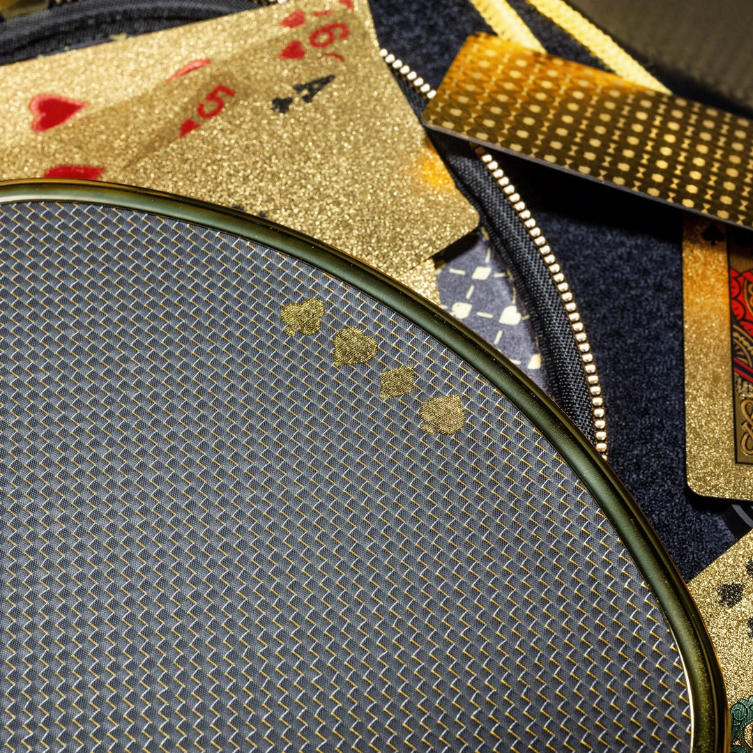 Original High Roller Hybrid paddle detail showing the gold card-suit artwork and black-and-gold woven face. Case and playing cards shown for styling; not included.