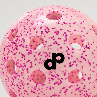 Macro close-up of pink glitter inside a translucent outdoor pickleball