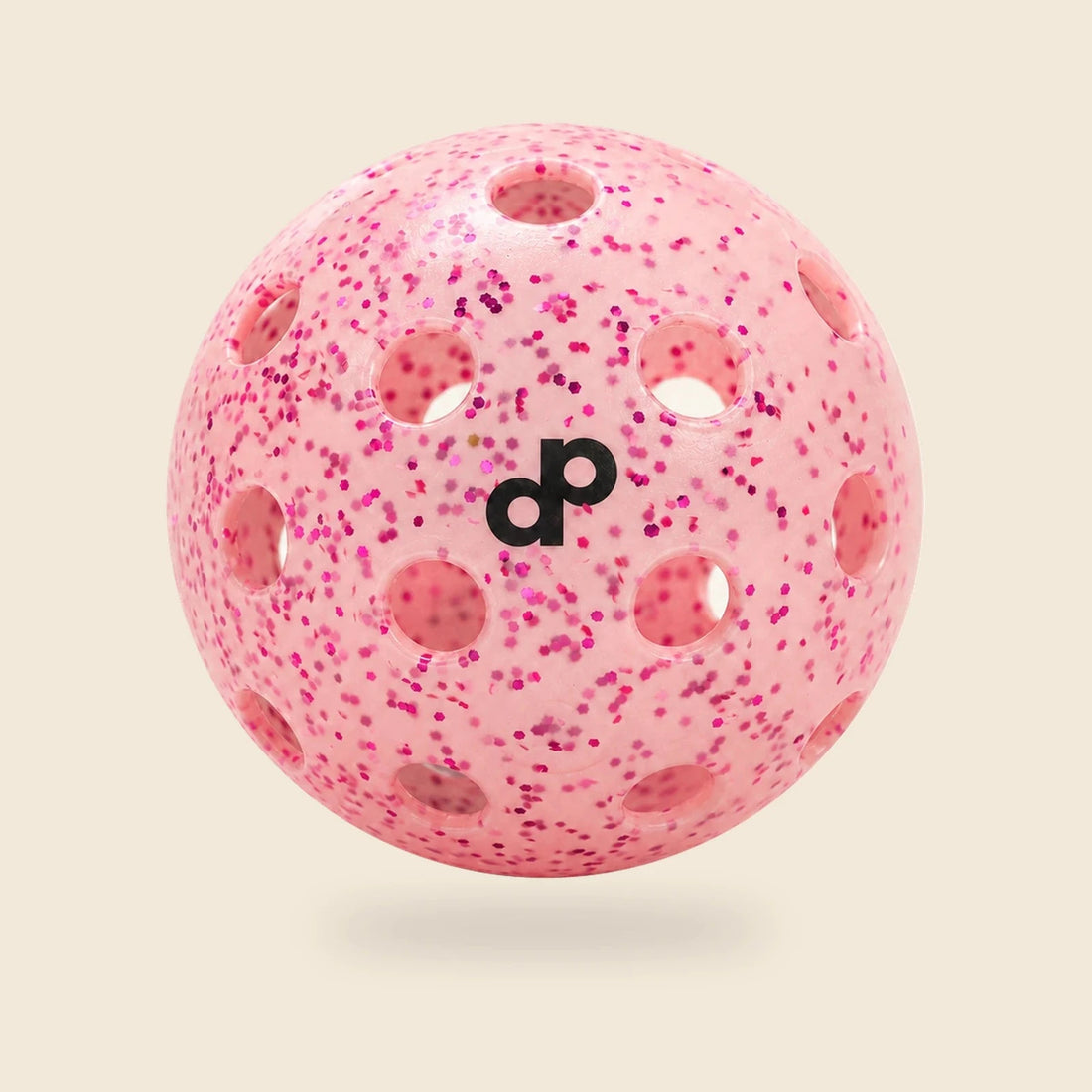 Single pink DOPE glitter pickleball with black DP logo and circular holes on a cream background.