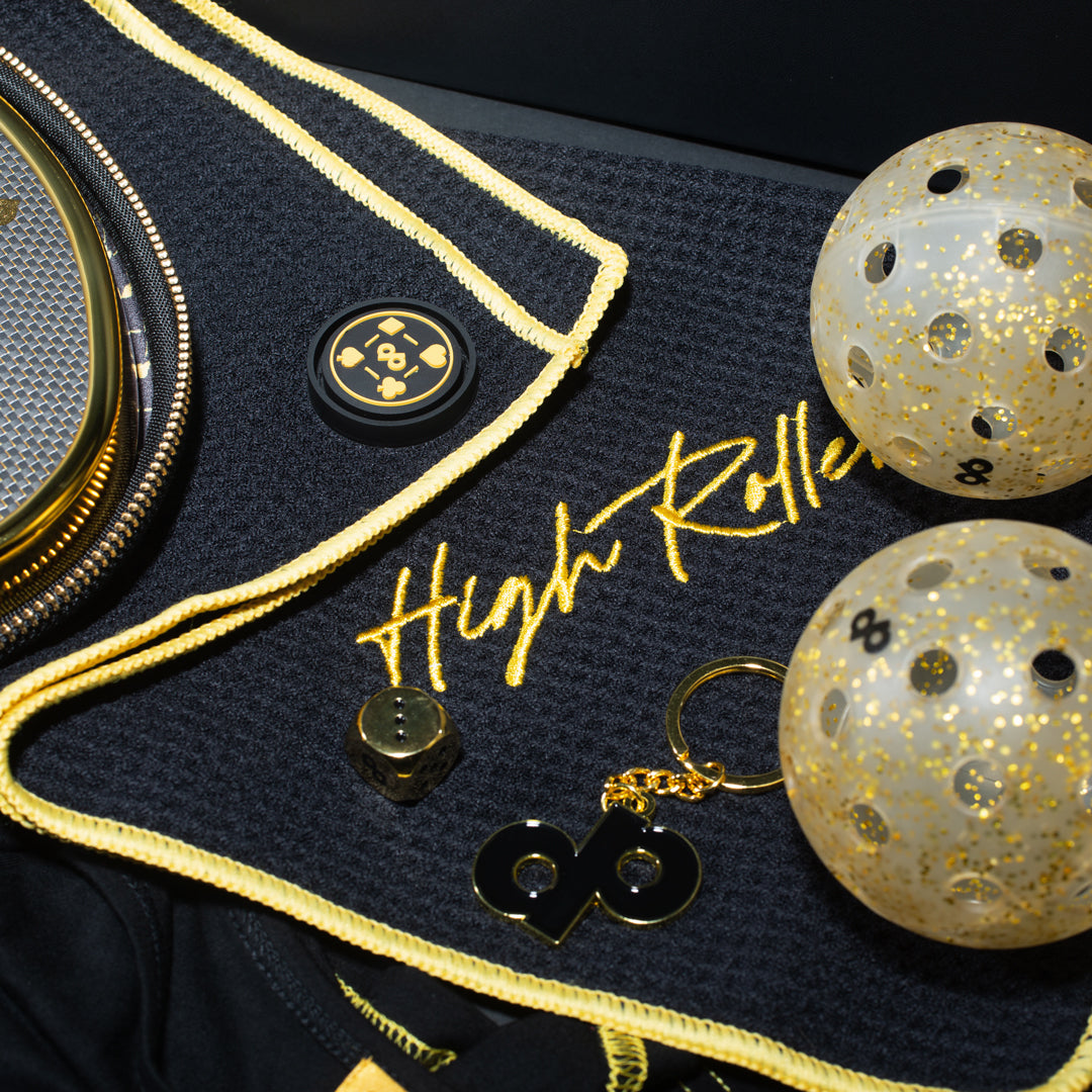 Black High Roller towel with gold trim, embroidered lettering and magnetic attachment; other accessories sold separately