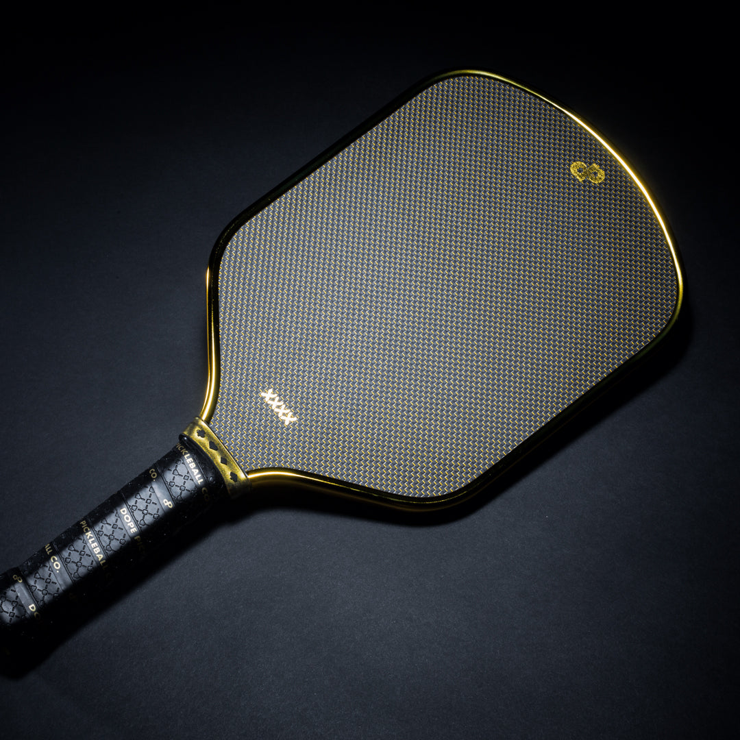 Black High Roller pickleball paddle face with a gold edge on a black background