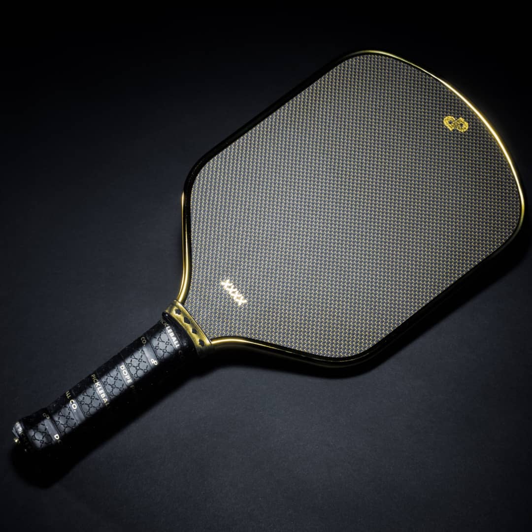 Angled view of a black High Roller pickleball paddle with a gold edge on a black background