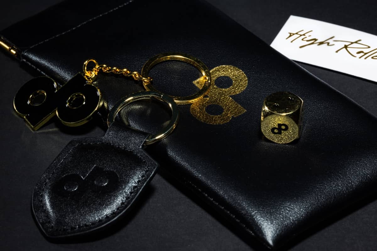 Gold-tone metal die with DOPE logo beside keychains and an accessory case sold separately