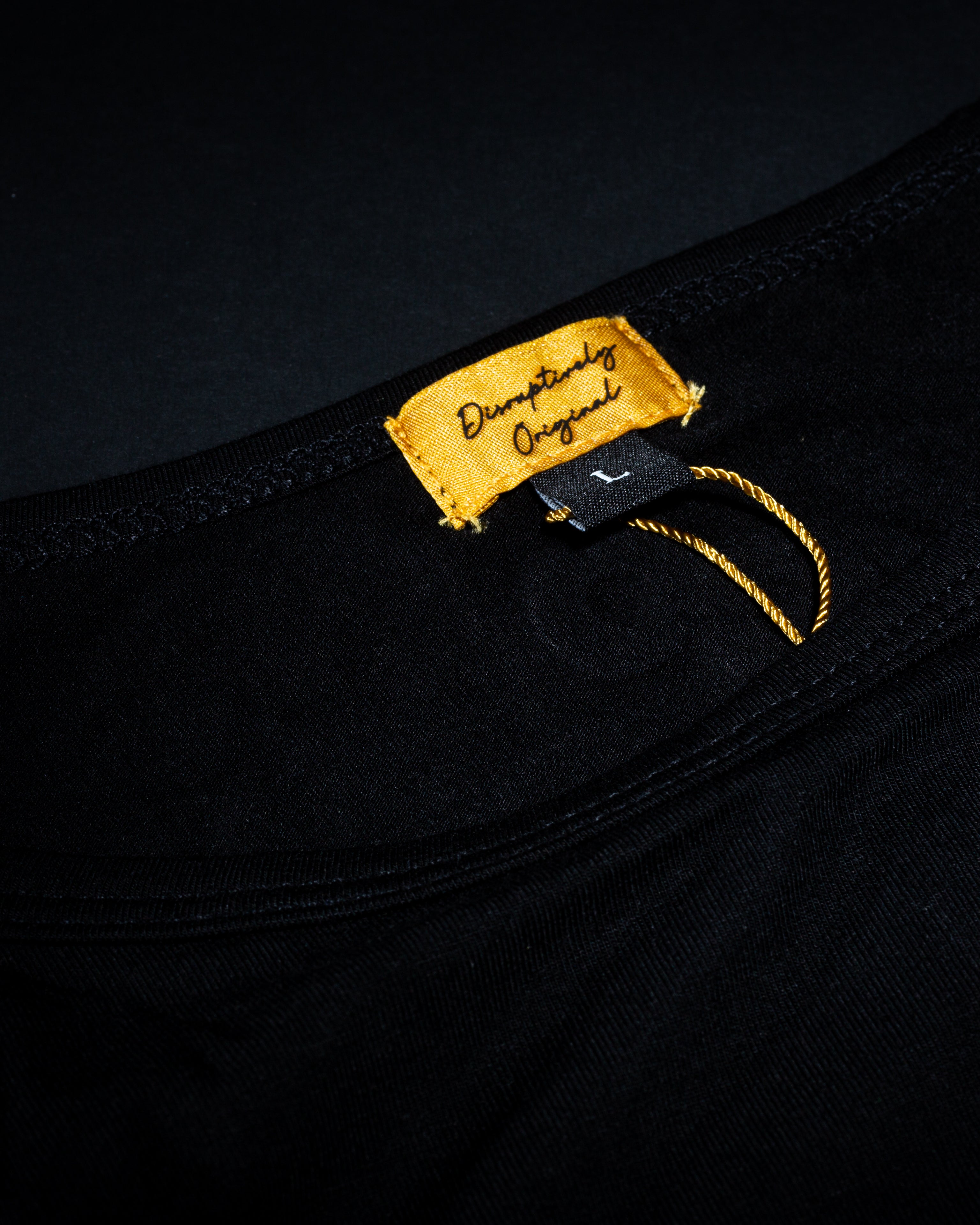 Close-up of a gold clothing label on the black High Roller T-shirt