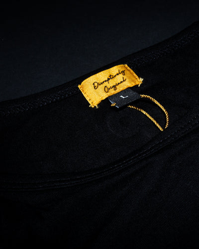 Close-up of a gold clothing label on the black High Roller T-shirt