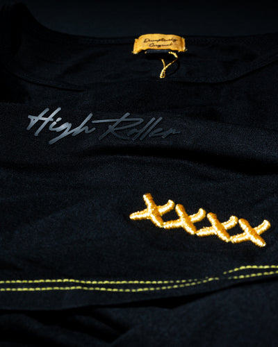 Close-up of High Roller script and gold stitch detail on a black T-shirt