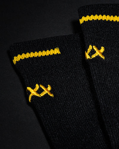 Close-up of black High Roller sock cuffs with gold stitch details