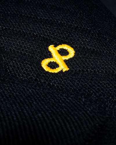 Close-up of a gold dp logo embroidered on black knit fabric