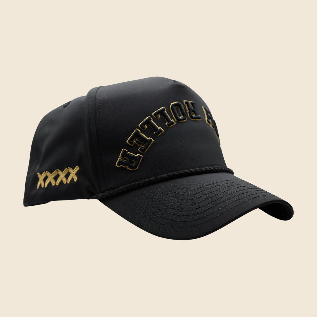 Three-quarter view of a black High Roller hat with gold lettering and gold side stitches