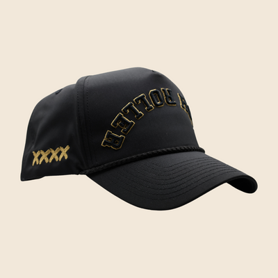Three-quarter view of a black High Roller hat with gold lettering and gold side stitches